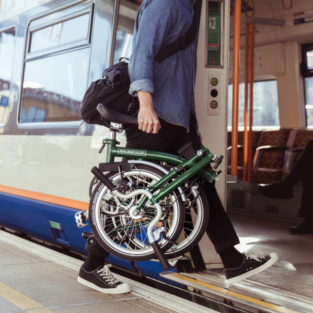 Man Boarding a Train Carrying a Folded Brompton Bike